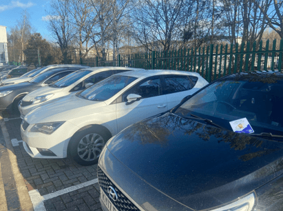 A row of cars with leaflets left on the windscreens