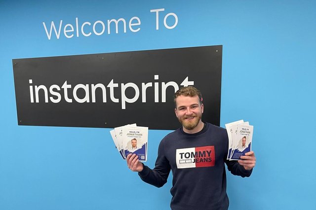 Newly hired marketing assistant holding the flyers from his stunt in the instantprint office