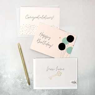 A flat lay featuring congratulations, happy birthday and new home greetings cards