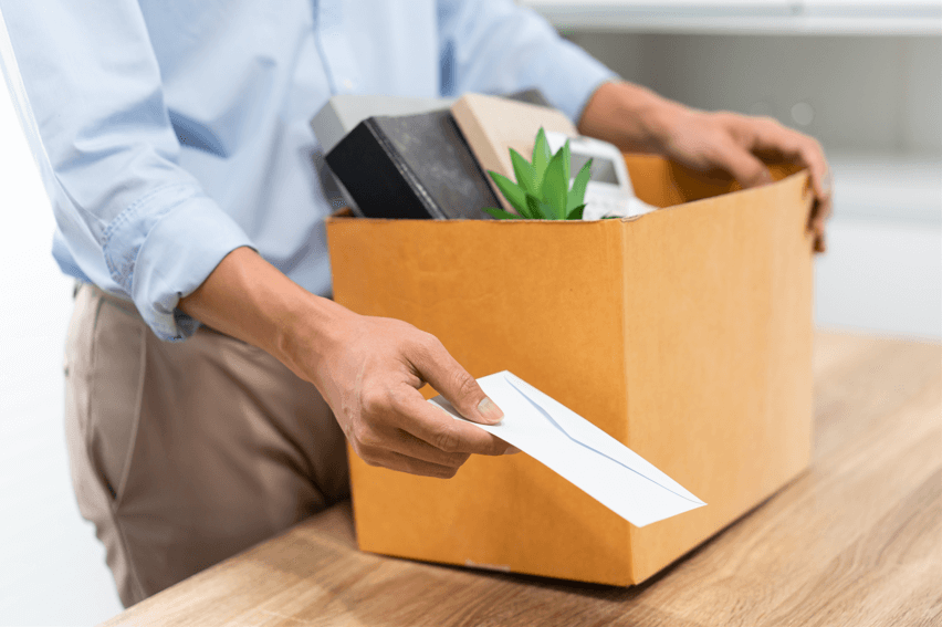 Man handing in a letter of resignation and holding a box of personal possessions