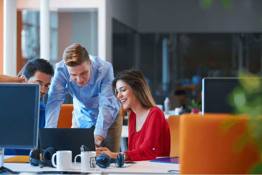 three office workers smiling at a computer screen