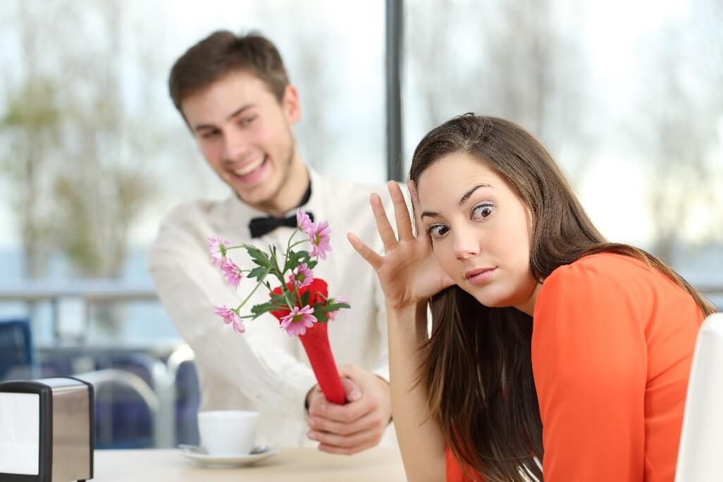 woman looking unimpressed at date handing her flowers