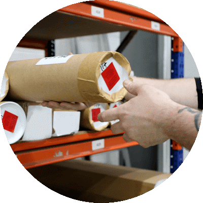 man sliding a poster tube off a packaging shelf