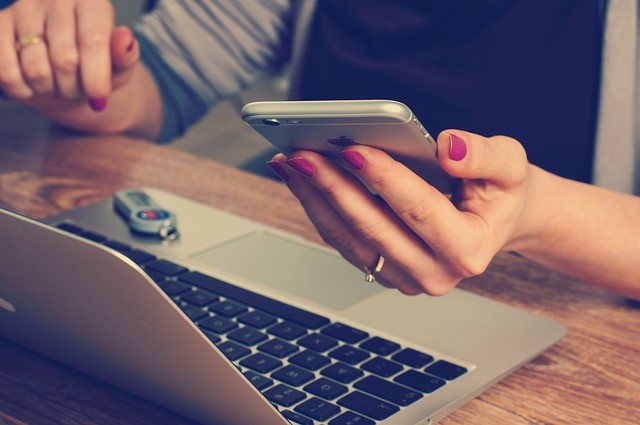 woman using a phone and laptop