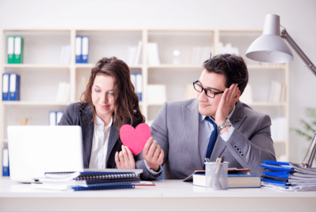 office man passing paper heart to female office worker