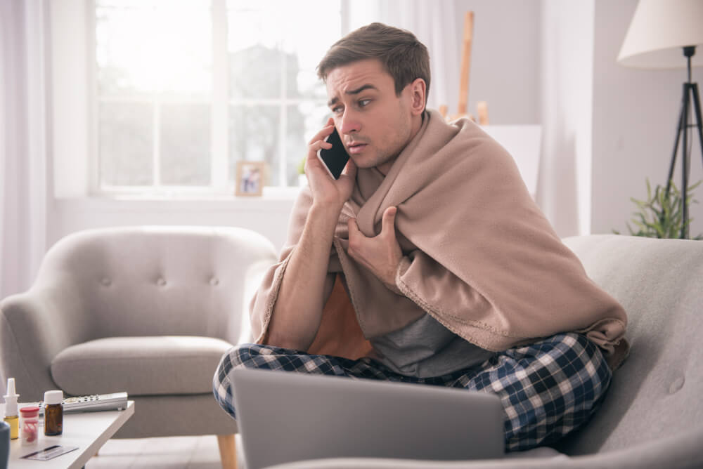 man in a blanket calling someone on the phone