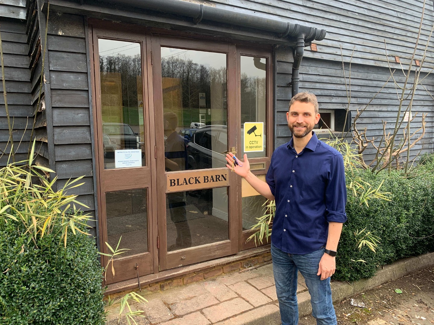 Simon Cornelius holding keys in front of new office space