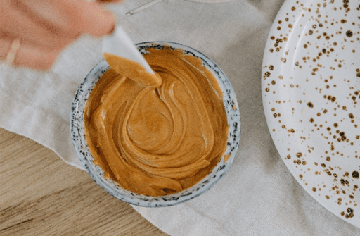 a bowl of peanut butter with a knife dipped in