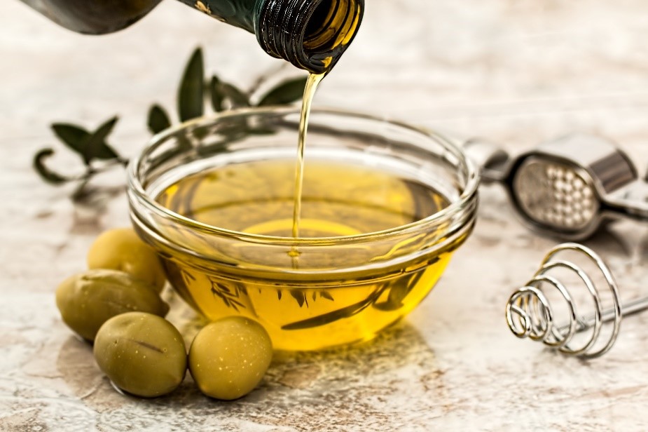 olive oil being poured into a clear bowl